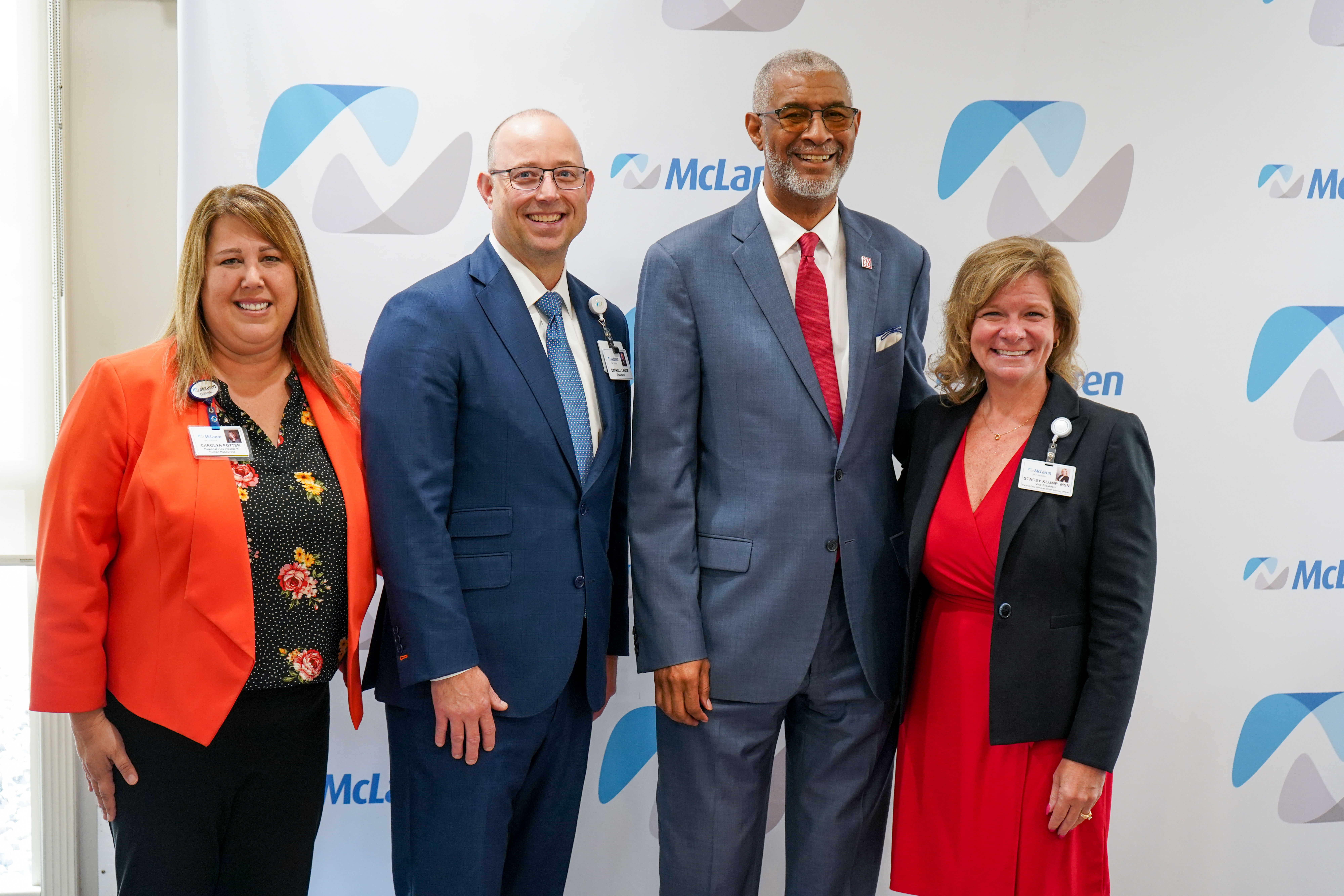 four people standing against McLaren Health Care backdrop